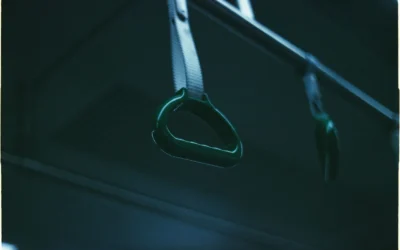 Close-up of subway train handrail in dim light, focusing on green handle.