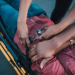 Close-up of a person securing an injured individual on a stretcher, providing emergency care.